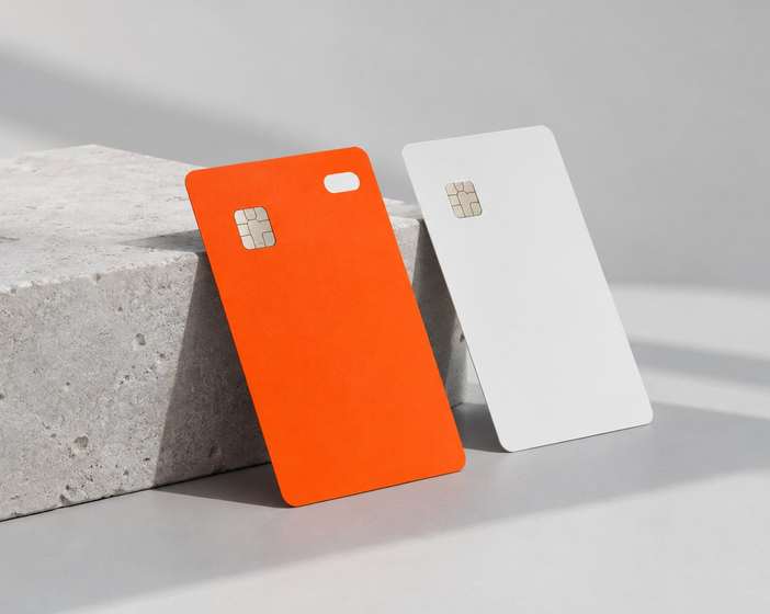 An orange and a white Mintline Bank card leaning against a concrete block
