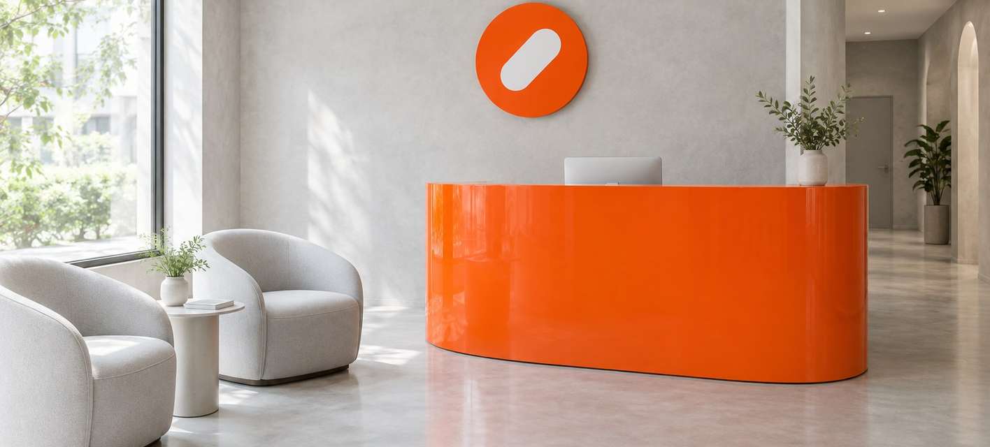 The Pulse Clinic reception with a curved orange desk, white armchairs and a round orange sign