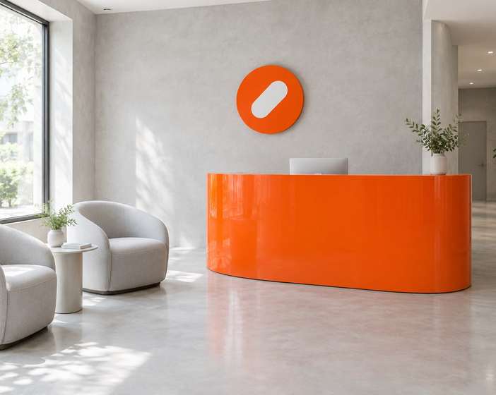 The Pulse Clinic reception with a curved orange desk, white armchairs and a round orange sign
