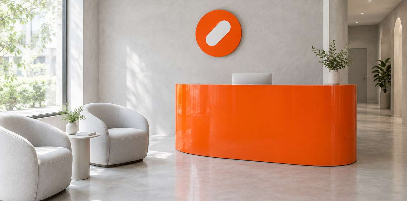 The Pulse Clinic reception with a curved orange desk, white armchairs and a round orange sign
