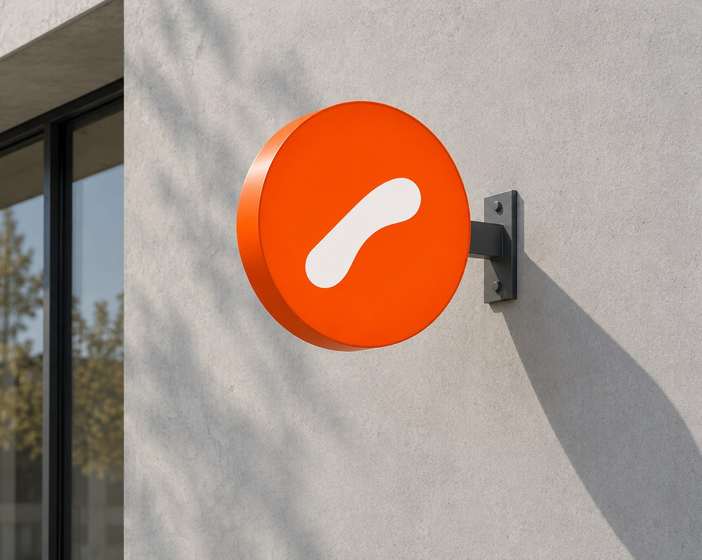 A round orange Orto Coffee sign with a white mark on a concrete facade