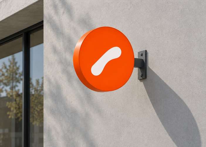 A round orange Orto Coffee sign with a white mark on a concrete facade