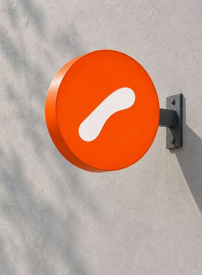 A round orange Orto Coffee sign with a white mark on a concrete facade
